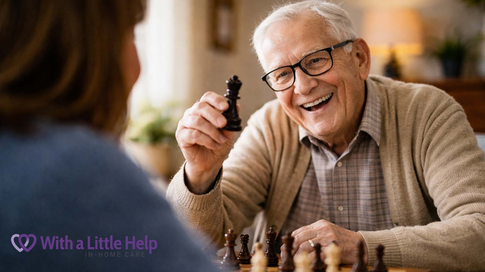 Senior enjoying a chess game at home with caregiver, highlighting interactive senior caregiving support